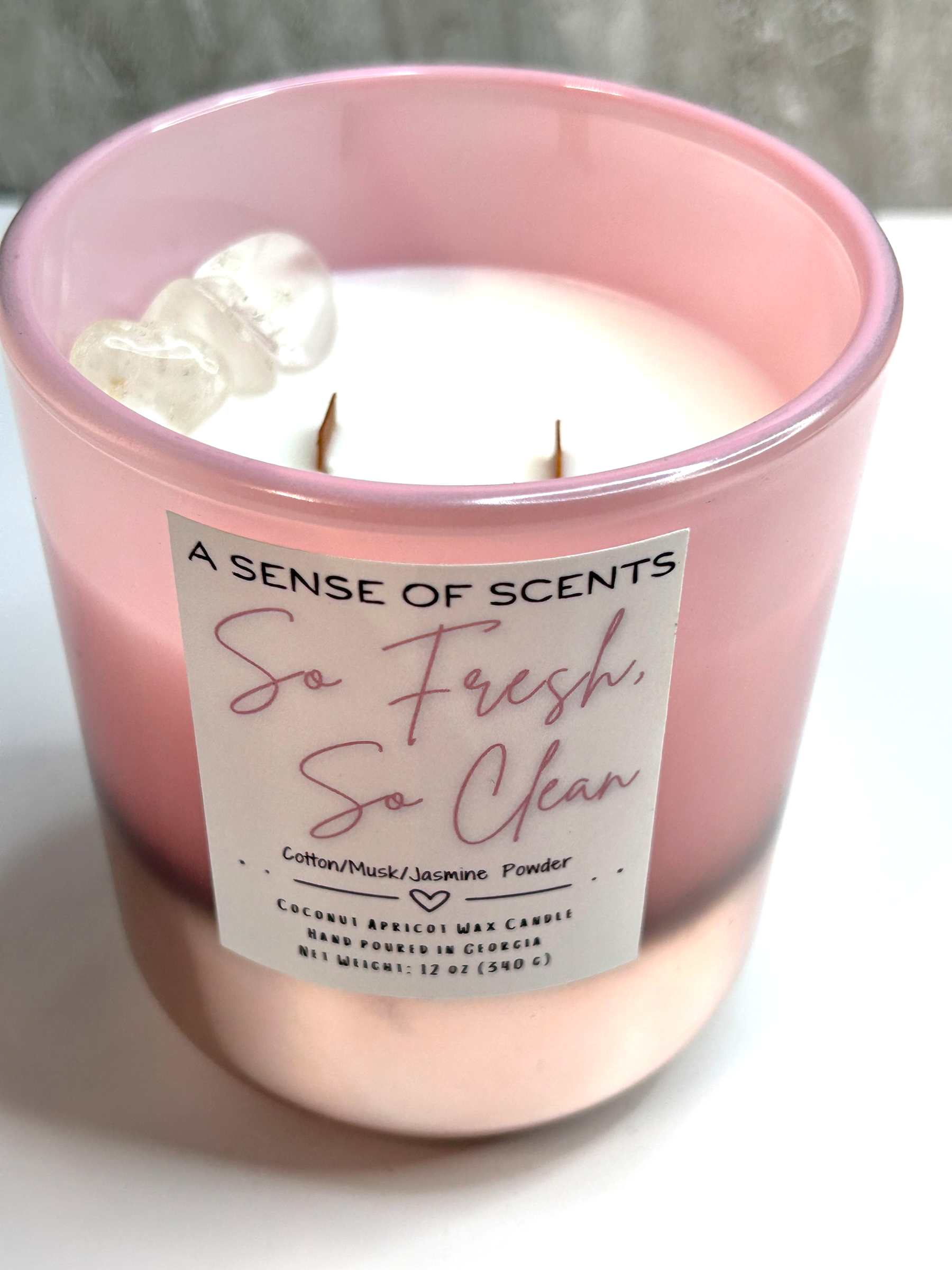 Pink candle labeled 'So fresh, so clean' on a white surface