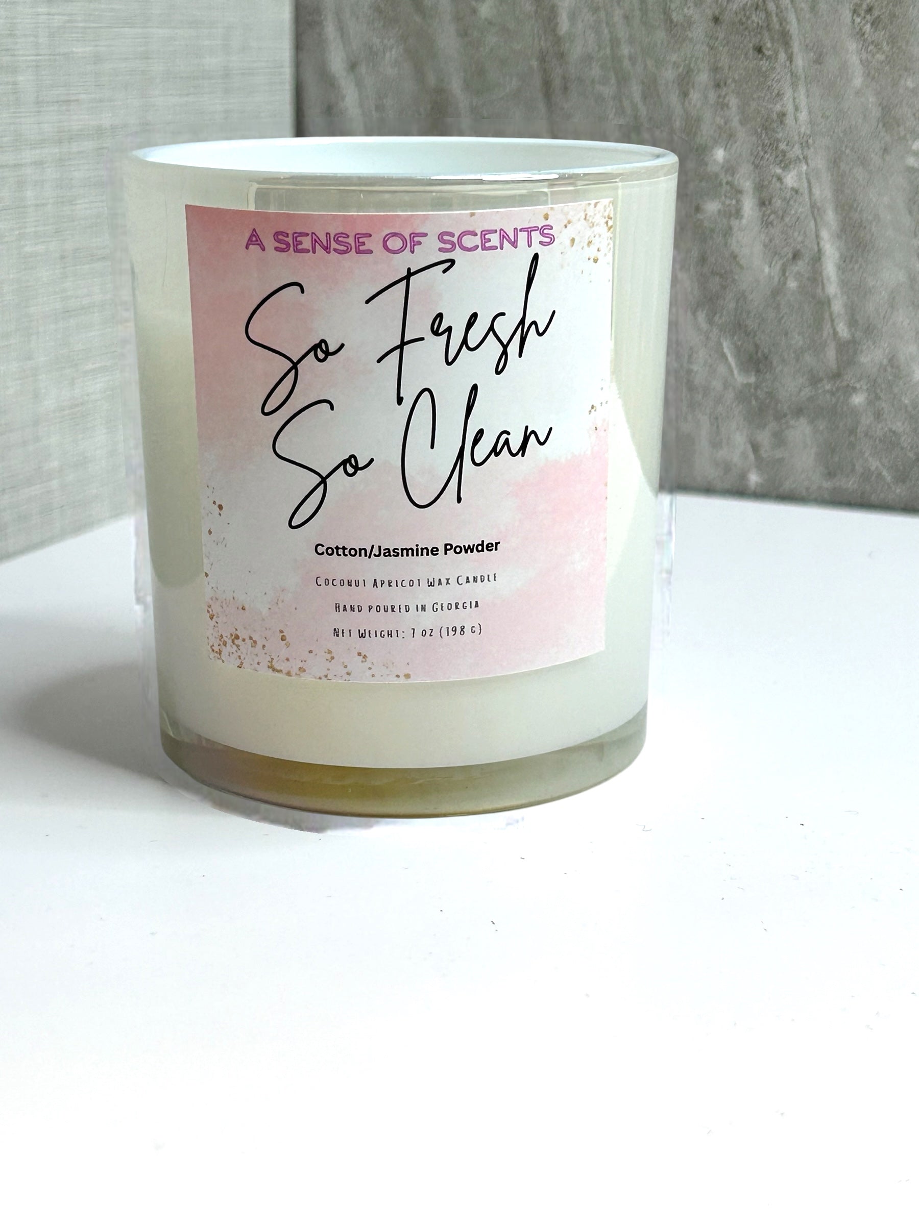 Candle with a label reading 'So Fresh So Clean' on a white surface.