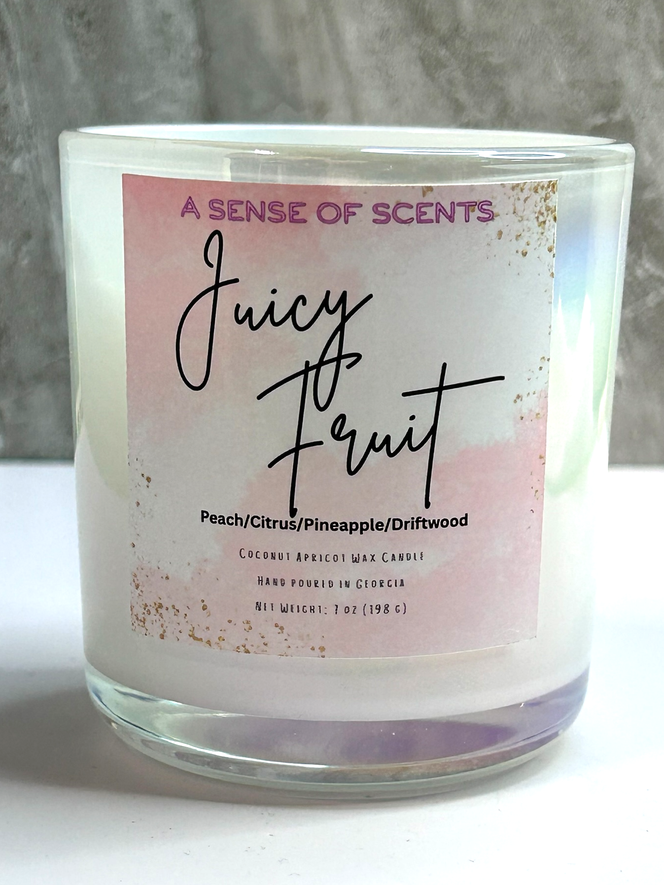 Candle with 'Juicy Fruit' label on a white surface and gray background