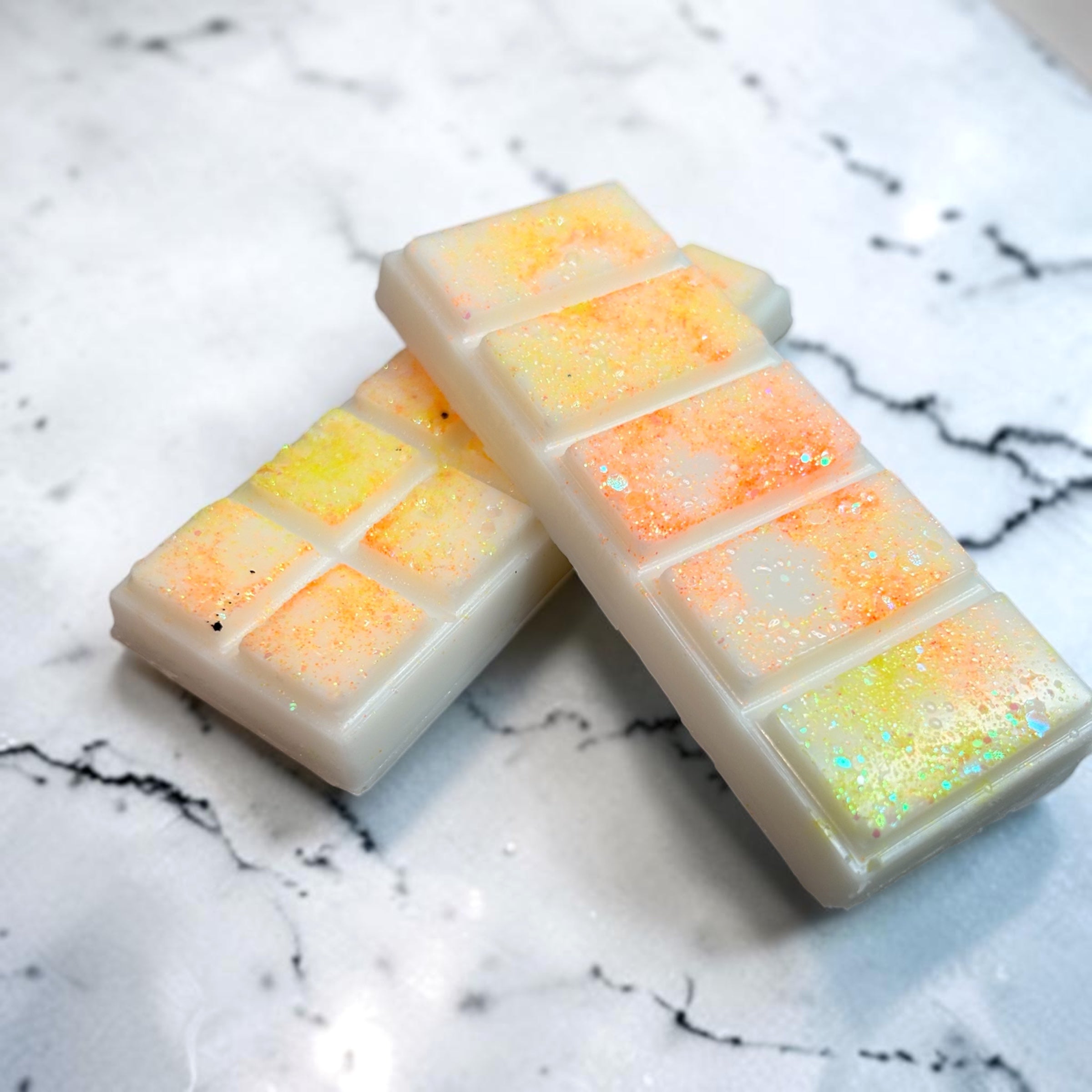 Two rectangular wax melts with colorful glitter on a marble surface