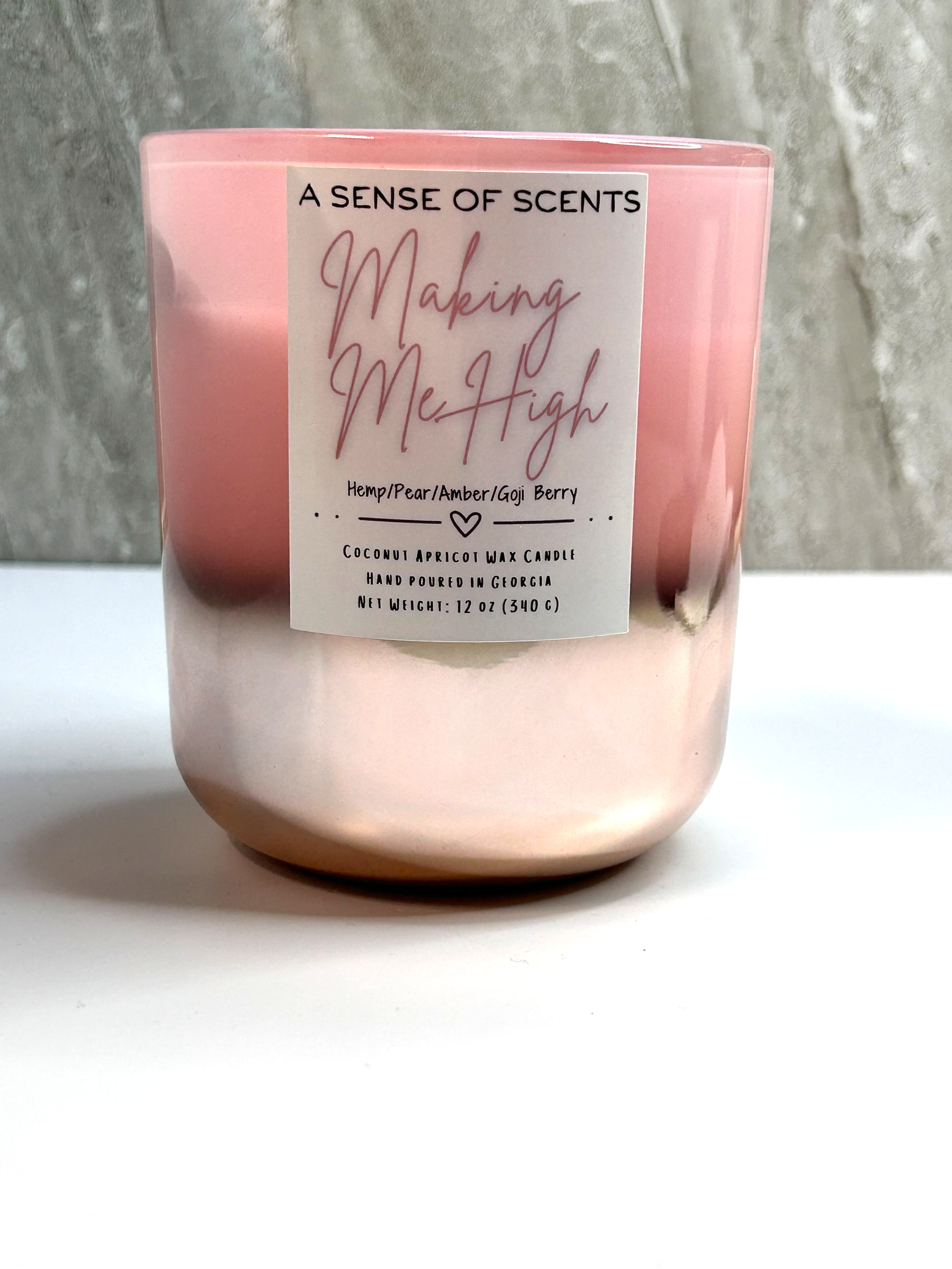 Pink candle labeled 'making me high' on a white surface