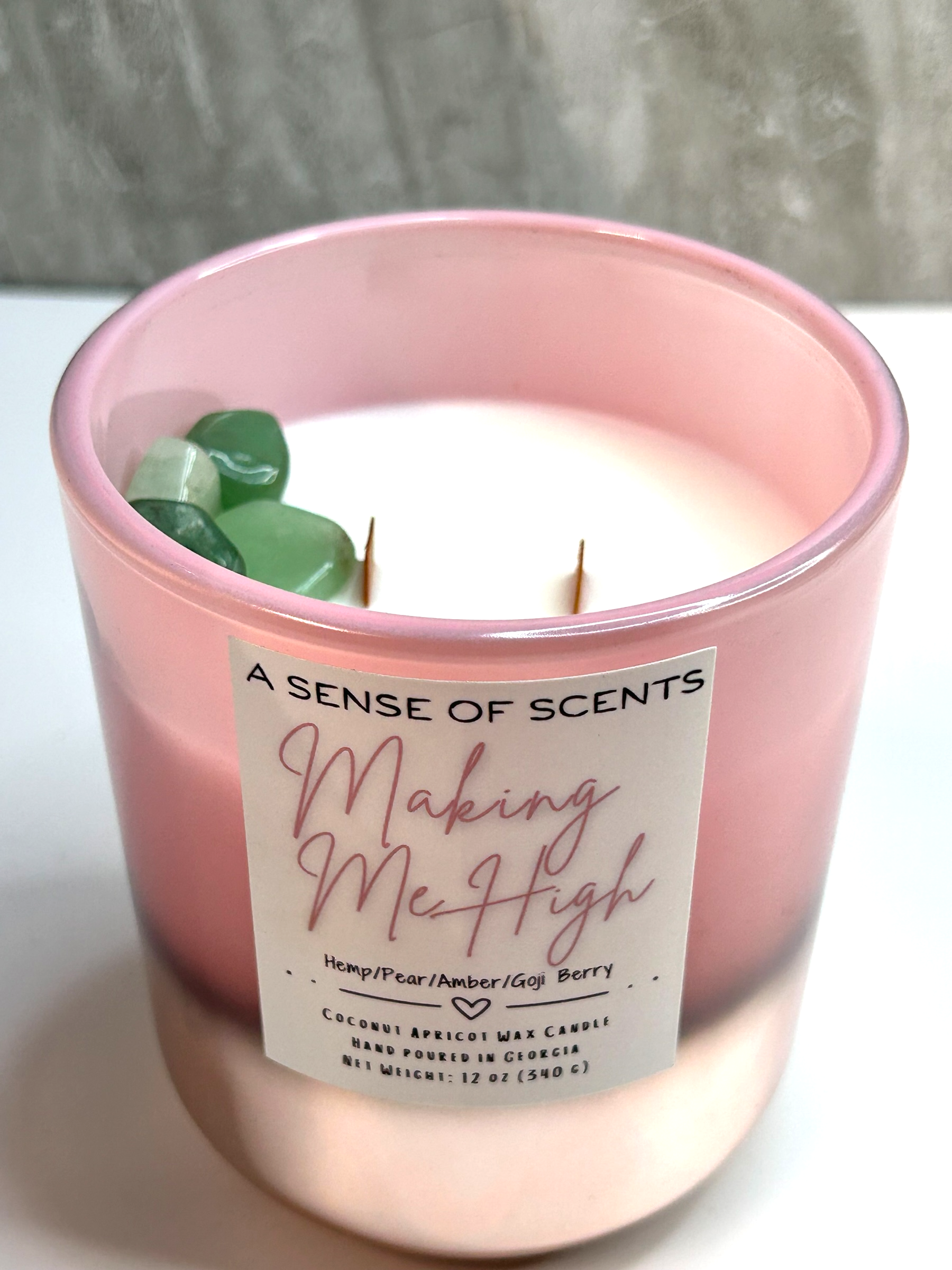 Pink candle labeled 'making me high' on a white surface