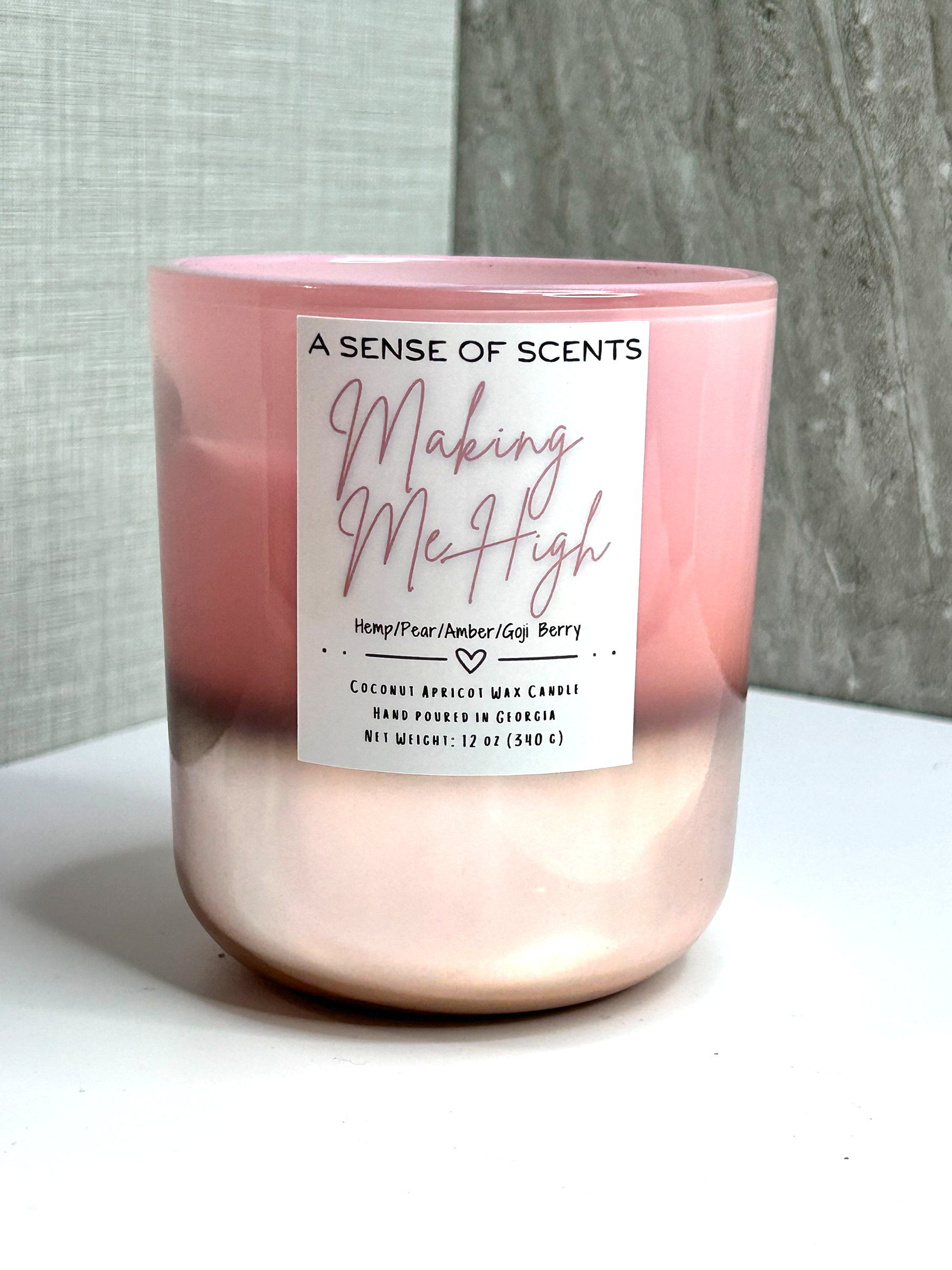 Pink candle labeled 'making me high' on a white surface