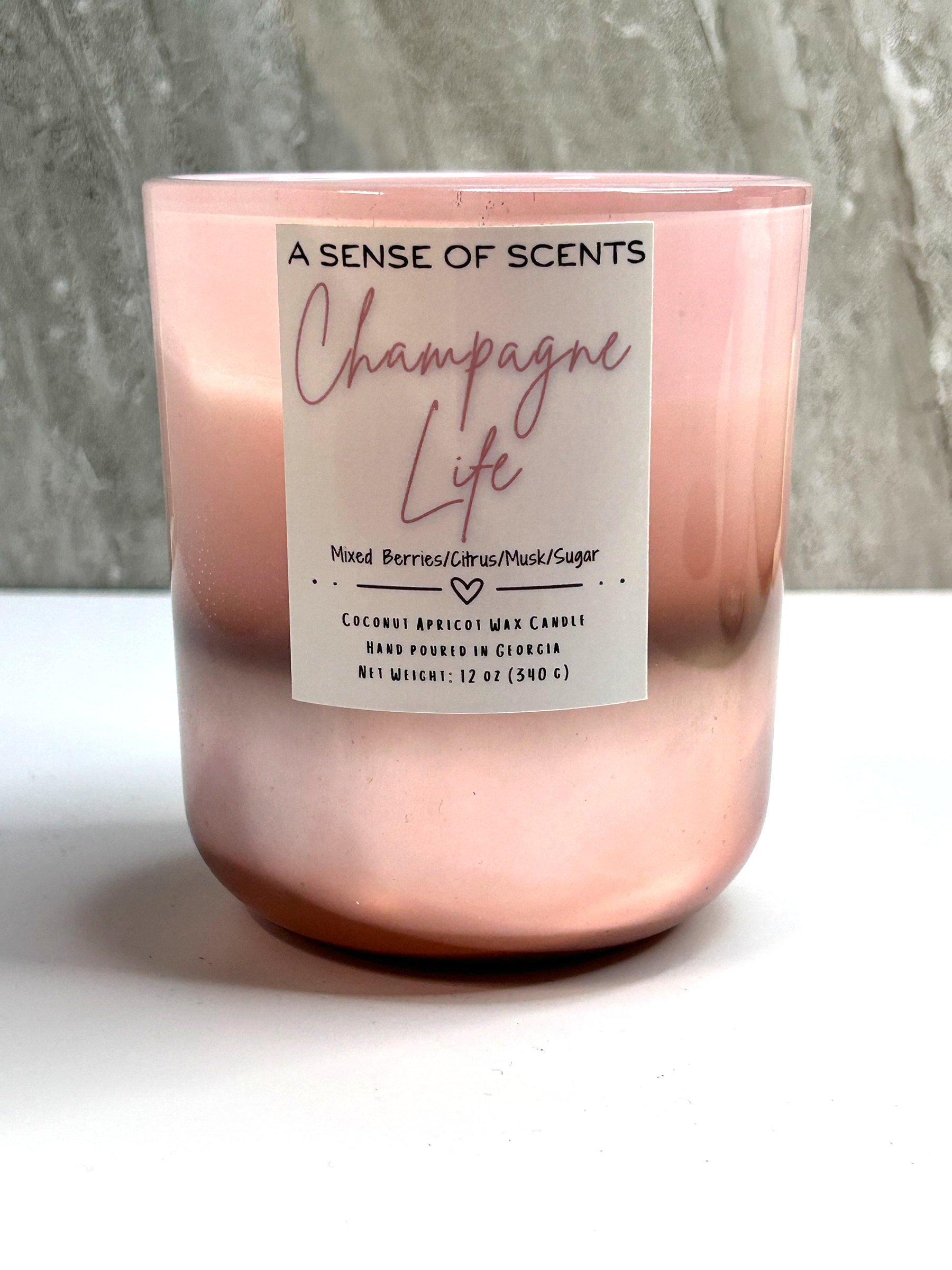 Pink candle labeled 'champagne life' on a white surface