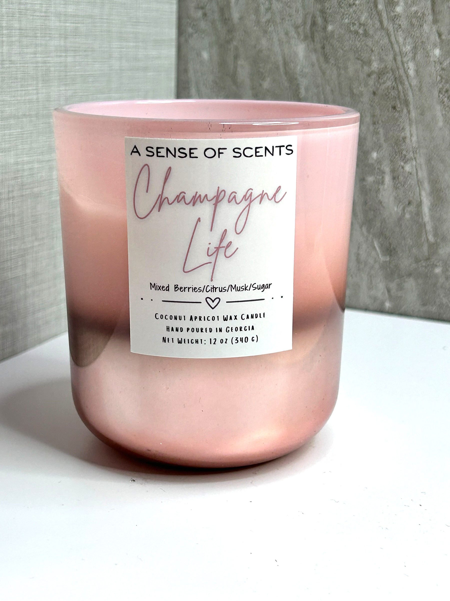 Pink candle labeled 'champagne life' on a white surface
