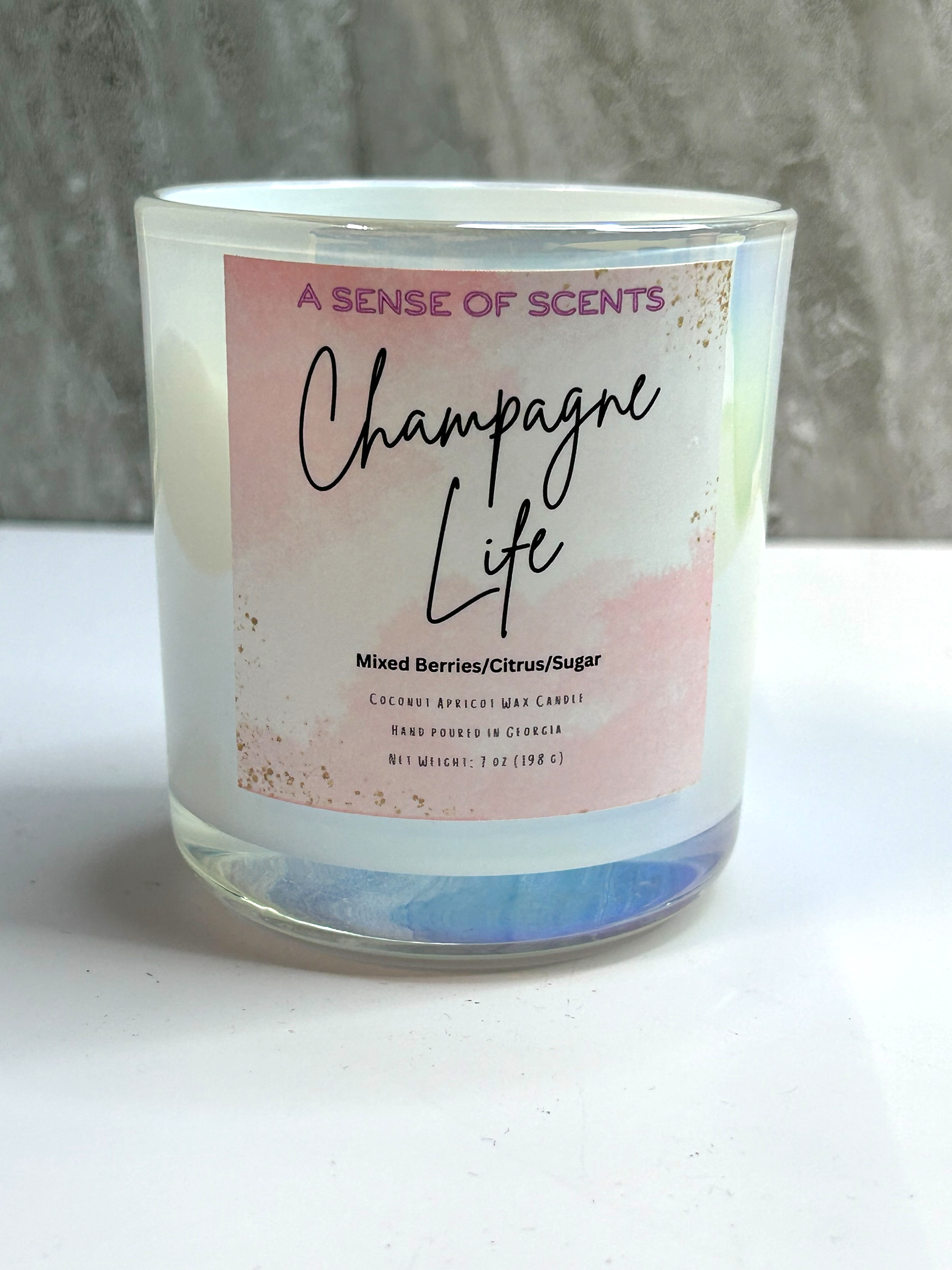 Candle with 'Champagne Life' label on a white surface and gray background