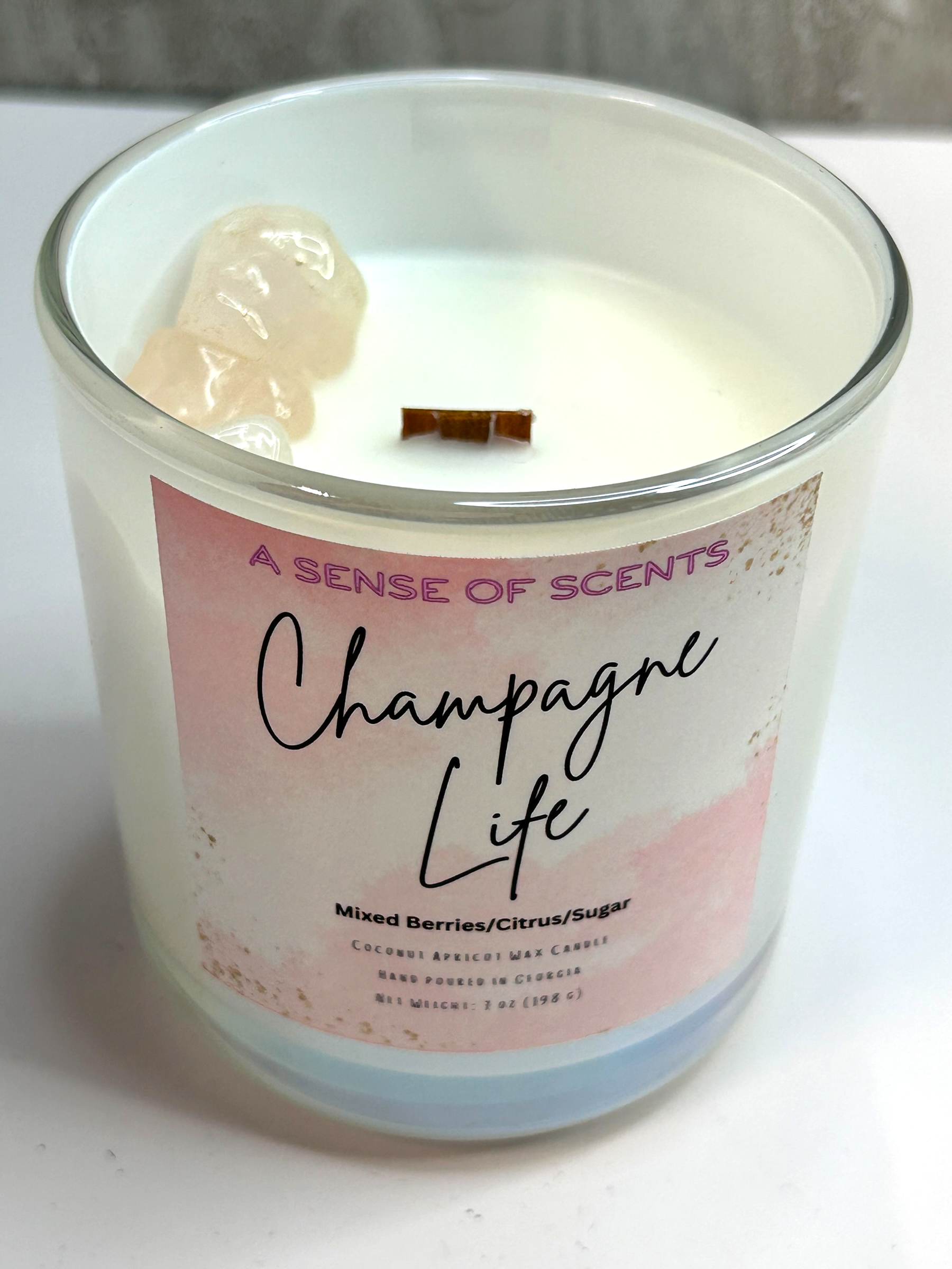 Candle in a glass jar labeled 'Champagne Life' by A Sense of Scents on a white background.