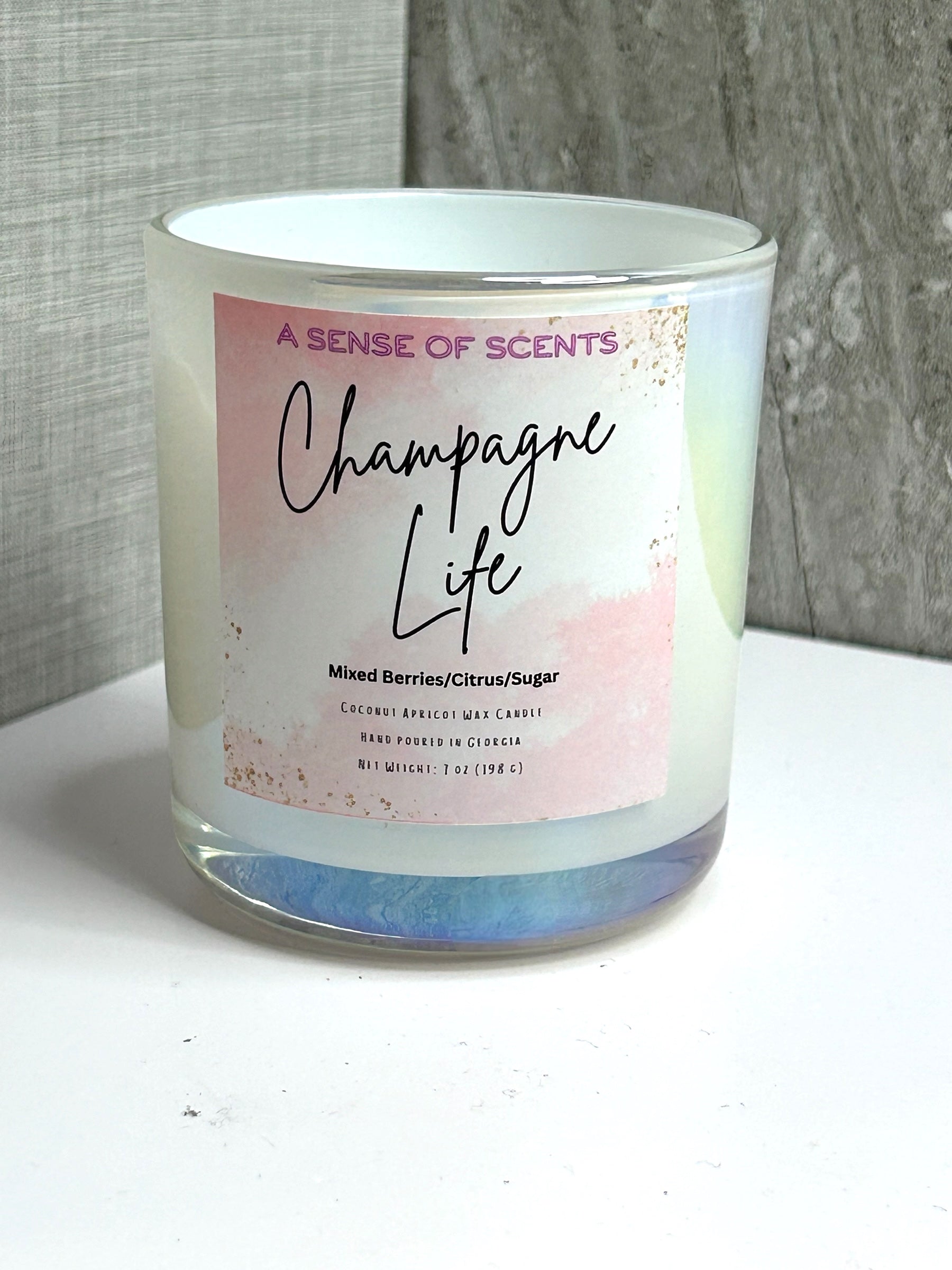 Candle with 'Champagne Life' label on a white surface and gray background