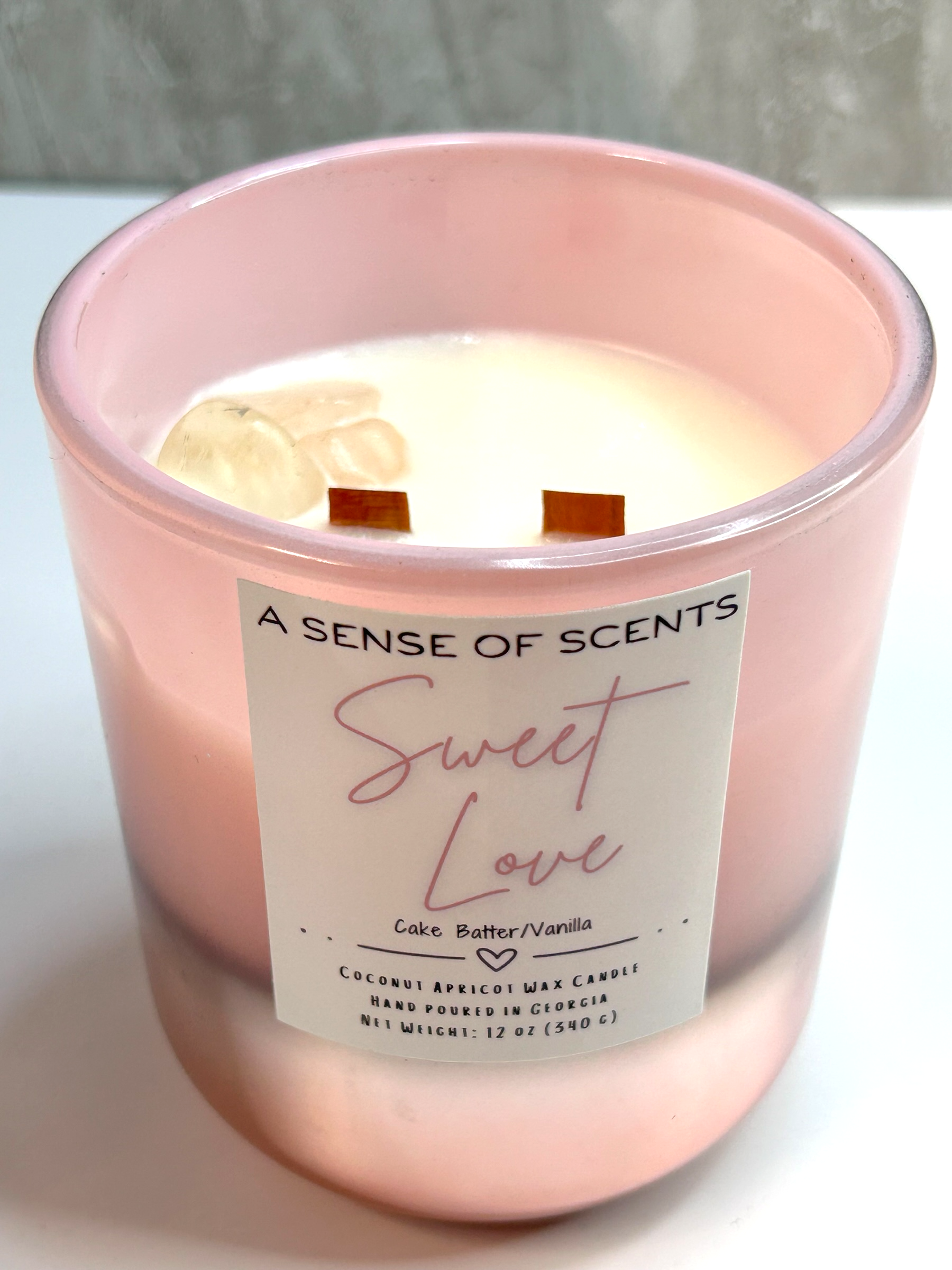 Pink candle labeled 'Sweet Love' with a soft focus background