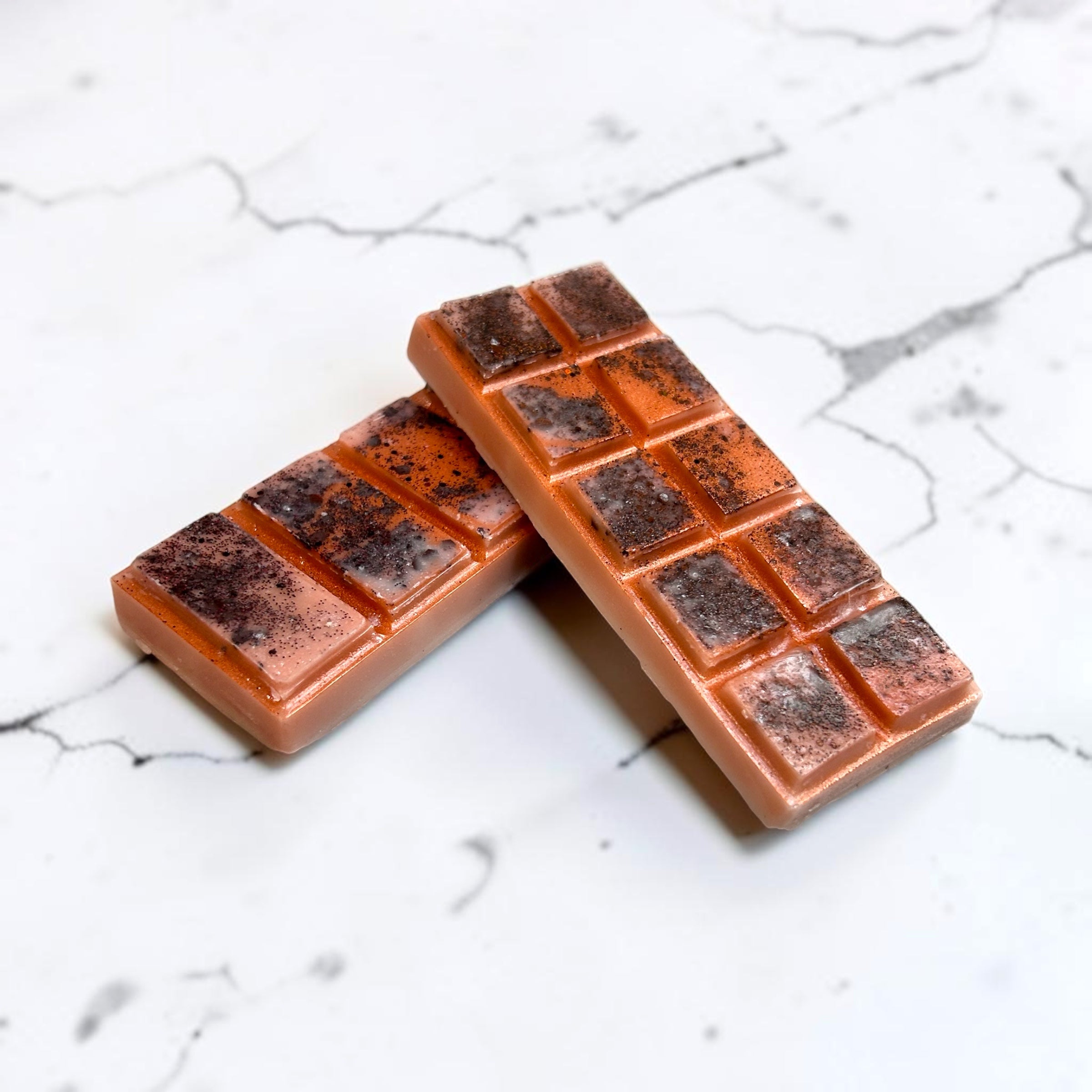 Two coconut was candle melts with a grid pattern on a marble surface