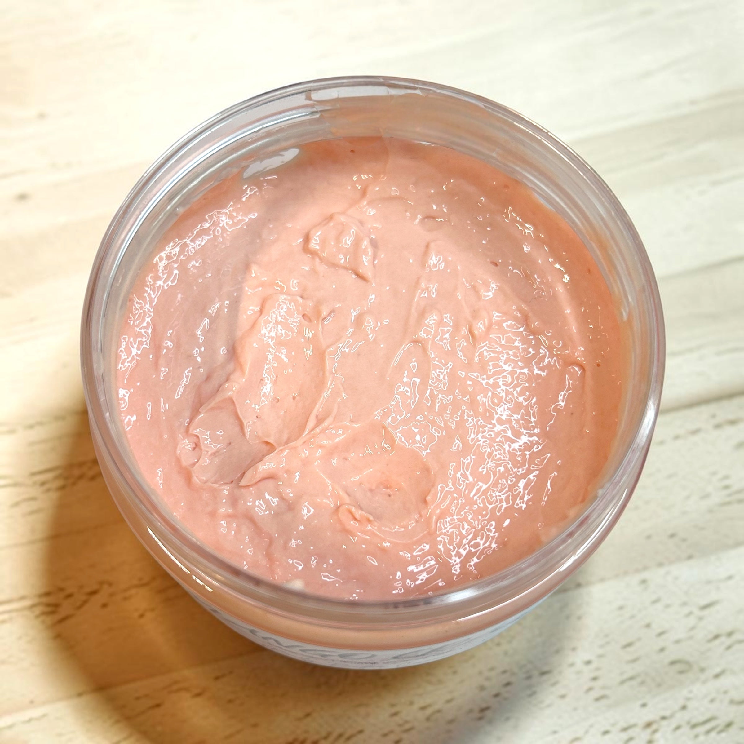 Jar of pink cream on a wooden surface