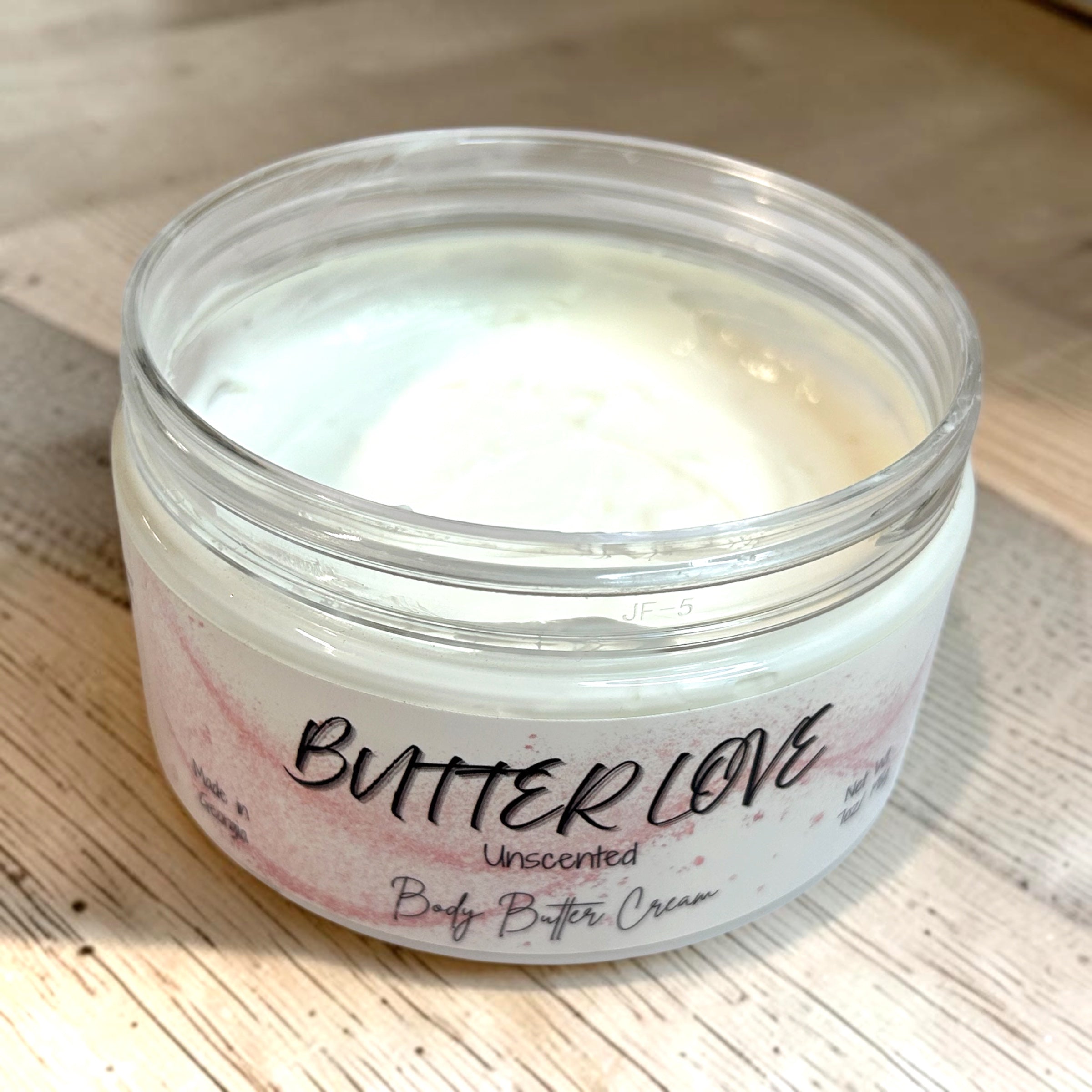 Jar of Butter Love unscented body butter cream on a wooden surface