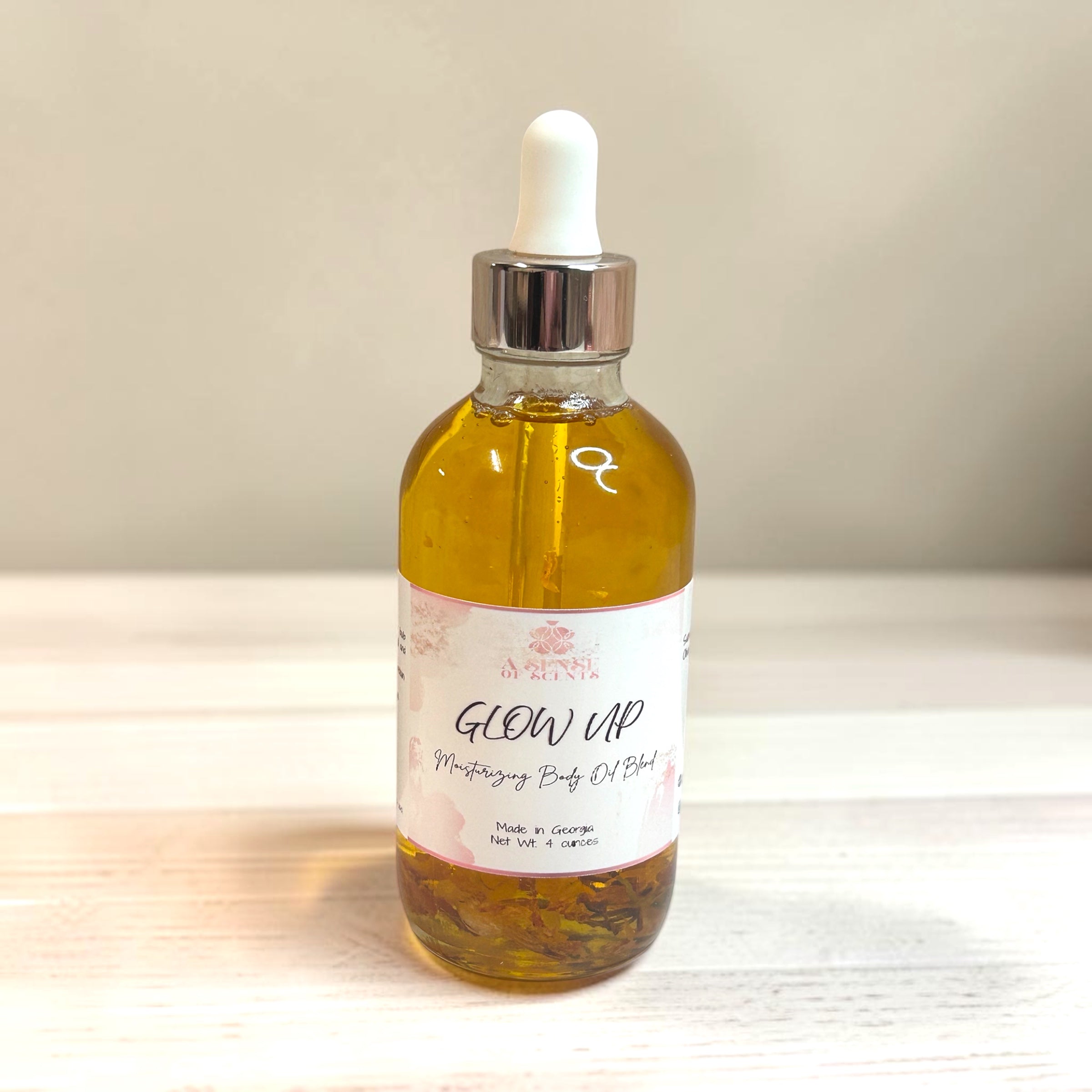 Bottle of 'Glow Up' moisturizing body oil blend on a neutral background