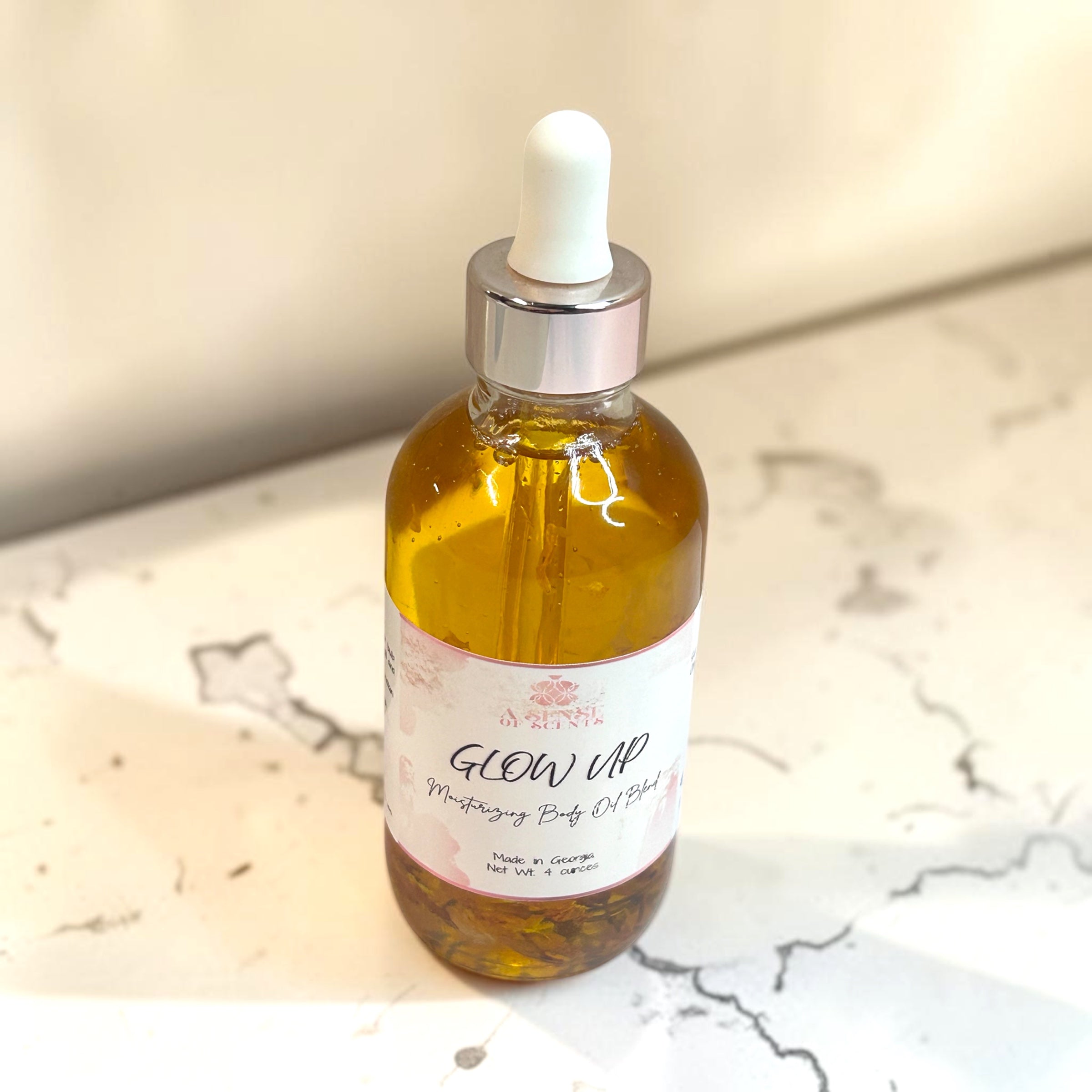 Bottle of 'Glow Up' moisturizing body oil on a marble surface