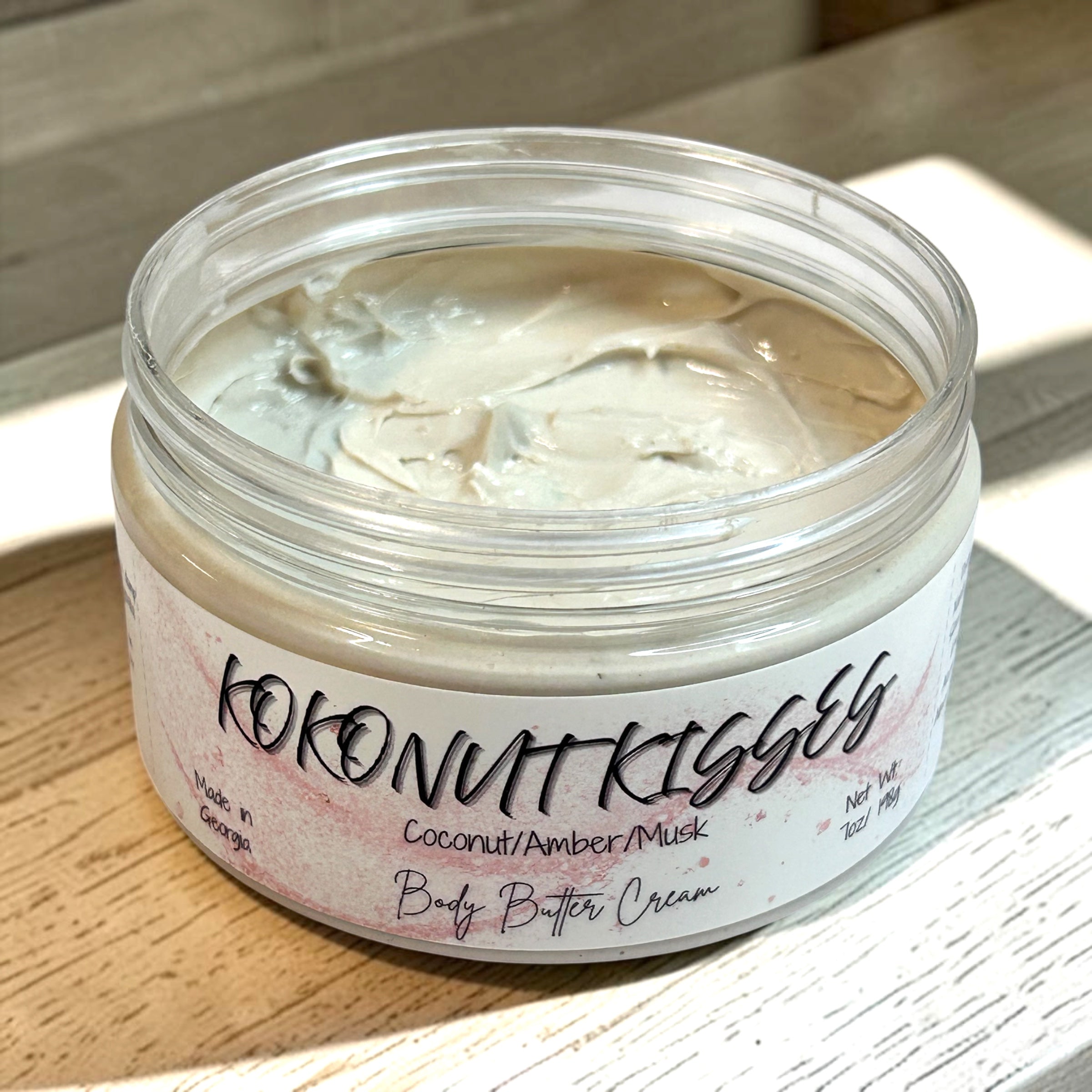 Jar of 'Kokonut Kisses' body butter cream on a wooden surface